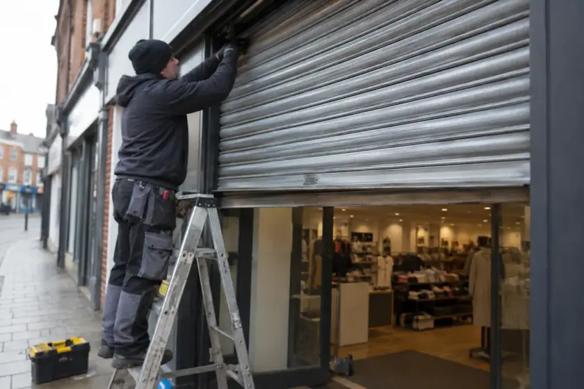 Illustrative Blast Film Installation Review scene: Engineer repairs jammed shopfront roller shutter.